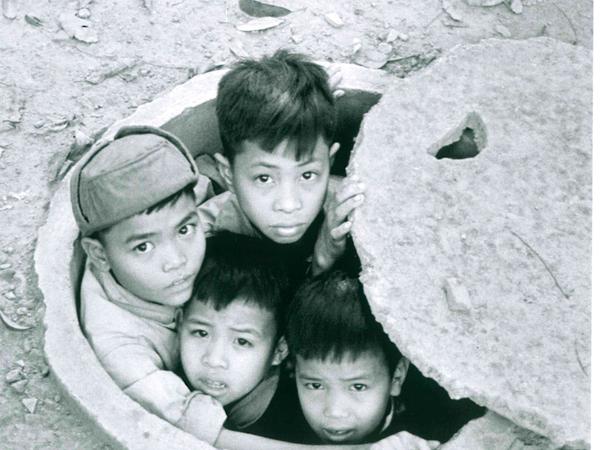 Ergreifend. Kinder suchen im vietnamesischen Hanoi in einem Gully Schutz vor den Bomben des Kriegs.