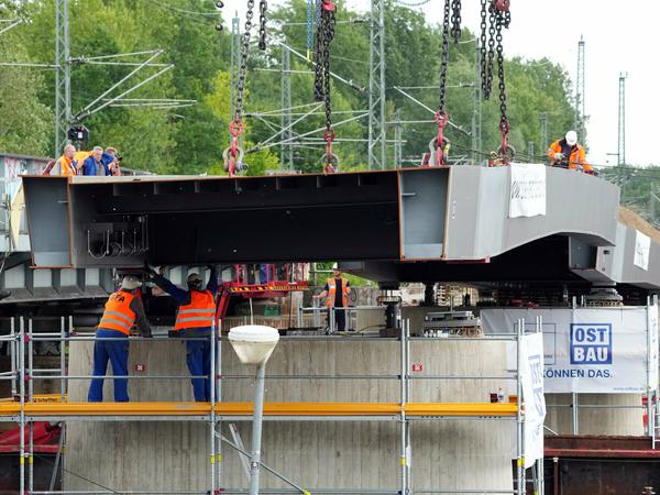 Arbeiter verfolgen das Einheben des Mittelstücks der Brücke.