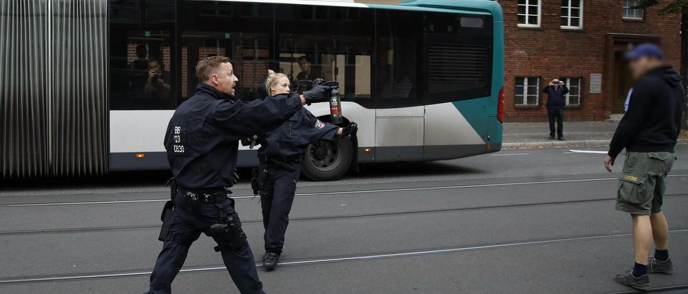 Polizisten sorgen mit gezücktem Pfefferspray für Ordnung bei Gegenprotesten gegen einen AfD-Infostand in Babelsberg.