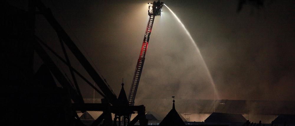 Feuer im Studio Babelsberg. Per Drehleiter versuchen Feuerwehrleute, den Brand im Dach der Filmhalle zu löschen.