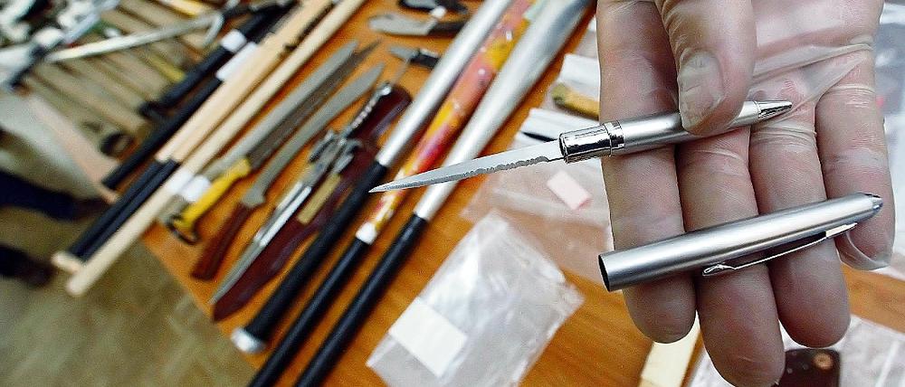 Heimtückische Waffe: Ein Polizist zeigt eine in einem Kugelschreiber versteckte Stichwaffe, die bei einer Razzia entdeckt wurde.