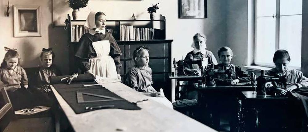 1910: Mädchen lernen in einem Rettungshaus in Rüdersdorf nähen. Aus diesen Häusern ging später das EJF hervor.