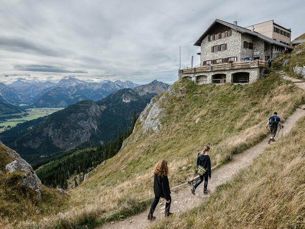 Wanderer gehen zu einer Hütte des Deutschen Alpenvereins (DAV).