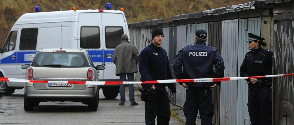 Polizisten stehen am Freitag in Potsdam auf dem Gelaende eines Garagenkomplexes, auf dem die Leiche eines Neugeborenen entdeckt worden war, hinter einem Absperrband. Ein Notarzt habe nur noch den Tod des Neugeborenen feststellen koennen, sagte eine Polizeisprecherin.