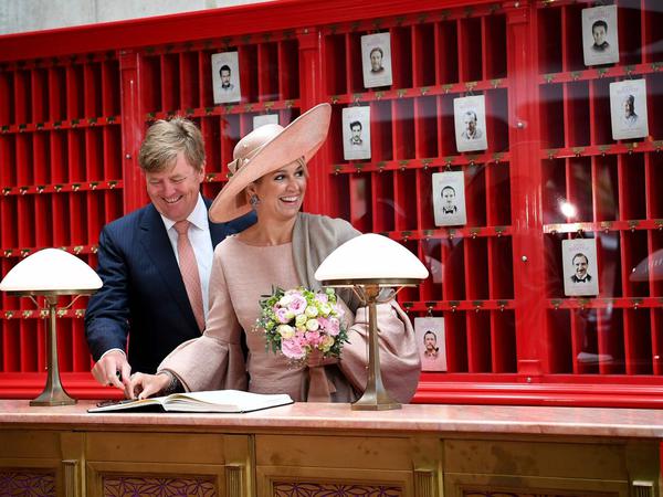 König Willem-Alexander und seine Frau Königin Maxima signieren ein Gästebuch vor Kulissen aus dem Film "Grand Budapest Hotel" in den Babelsberger Filmstudios.
