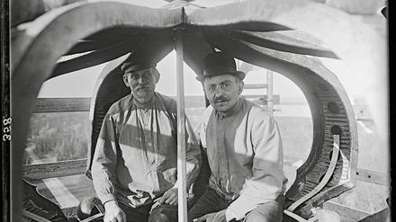 Zwei Handwerker in der Krone auf dem Dach des Neuen Palais' (um 1910).