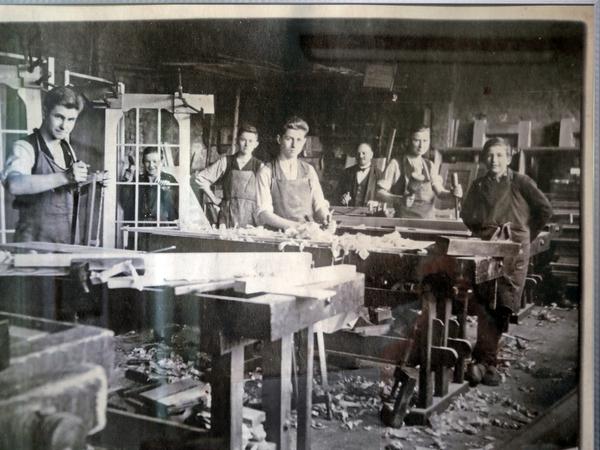 Bild im Firmenbüro mit Firmengründer Werner John (mitte) als Tischlerlehrling 1928 in seinem Ausbildungsbetrieb ebenfalls in Babelsberg.