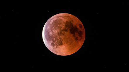 Der teilweise vom Erdschatten verdunkelte Vollmond leuchtet während einer Mondfinsternis rot bis orange.