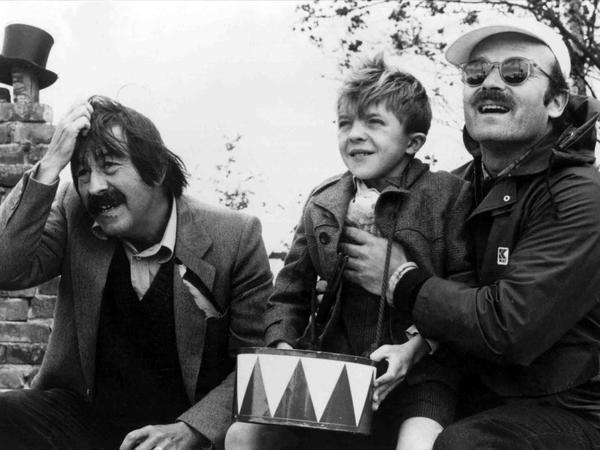 Die Aufnahme aus dem Jahr 1979 zeigt den Schriftsteller Günter Grass (v.l.), Schauspieler David Bennent als Blechtrommler Oskar Mazerath und Regisseur Volker Schlöndorff während einer Drehpause zu dem Film "Die Blechtrommel".