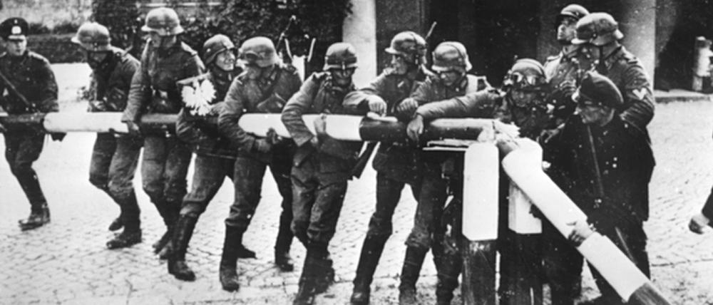 Beim Einmarsch in Polen am 1.9.1939 reißen Soldaten der deutschen Wehrmacht einen Schlagbaum an der deutsch-polnischen Grenze nieder. Am selben Tag verkündet Hitler vor dem Berliner Reichstag mit dem Ausspruch "Seit 5.45 Uhr wird zurückgeschossen..." den Ausbruch des Zweiten Weltkriegs.