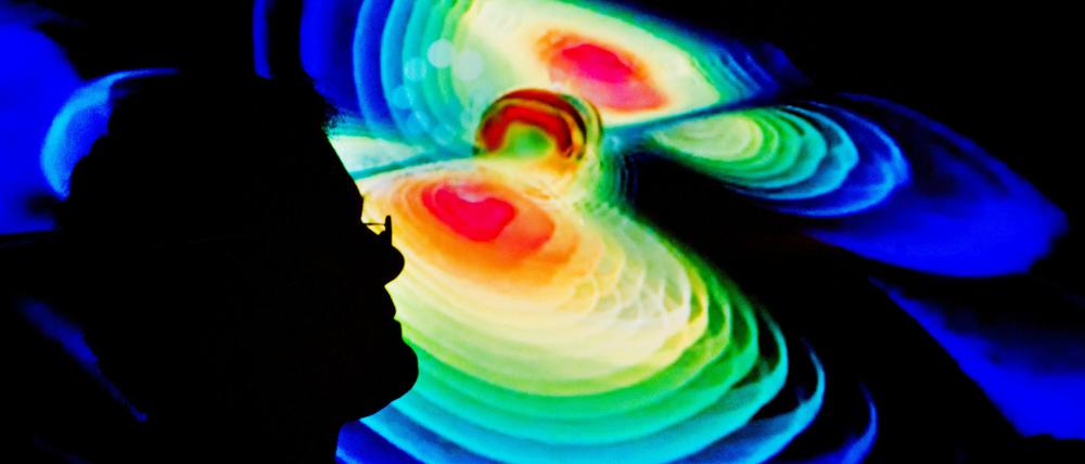 Der Schattenriss eines Wissenschaftlers vor einer Visualisierung von Gravitationswellen am Max-Planck-Institut für Gravitationsphysik (Albert Einstein Institut) in der Leibniz Universität in Hannover.