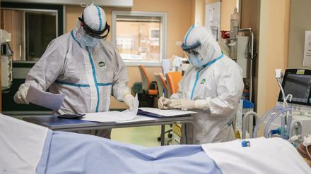 Ein Arzt und eine Krankenschwester in Schutzkleidung arbeiten auf einer Intensivstation.