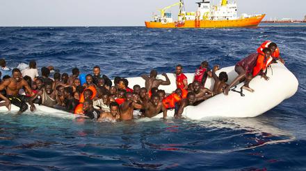Flüchtlinge sitzen auf dem Mittelmeer in einem sinkenden Schlauchboot. 