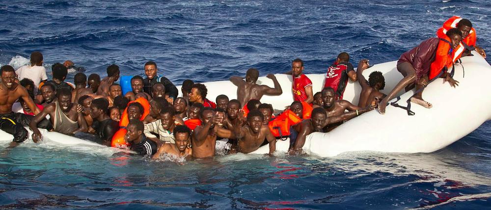 Flüchtlinge sitzen auf dem Mittelmeer in einem sinkenden Schlauchboot. 