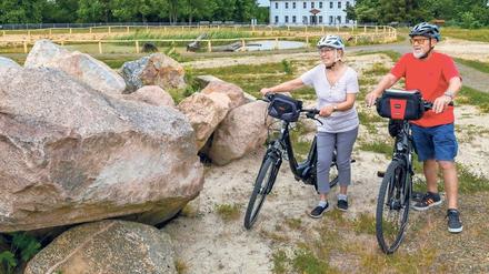 Die Urlauber Uta Trost und Andreas Schuster stehen mit ihren Fahrrädern neben Findlingen am rekultivierten Geisendorfer Berg.