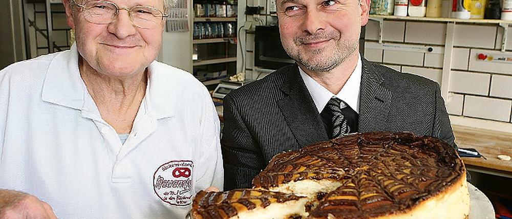 Locker und leicht: Mit dieser Torte will Gerd Neuendorff (l.) die Jury beim Käsekuchen-Wettbewerb überzeugen. Bei Bürgermeister Thomas Schmidt (r.), der einst in seiner Bäckerei lernte, hat er schon gewonnen.