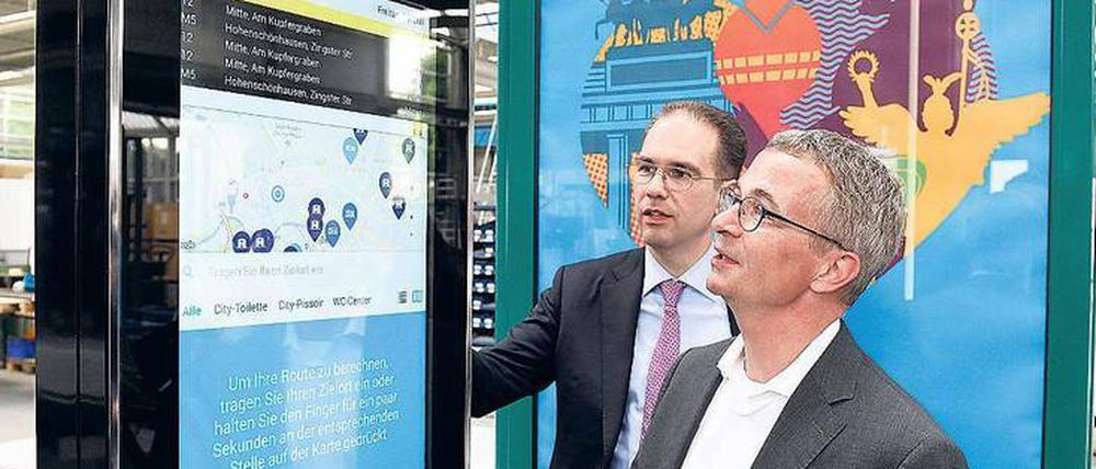  Brandenburgs Wirtschaftsminister Albrecht Gerber (rechts, SPD) lässt sich in der Fabrik des Außenwerbers Wall von Geschäftsführer Patrick Möller eine digitale Anzeige erklären. 