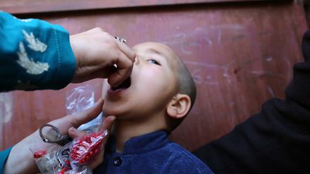 Der 3-jährige Moheburrahman aus Afghanistan bekommt die Polio-Schluckimpfung.