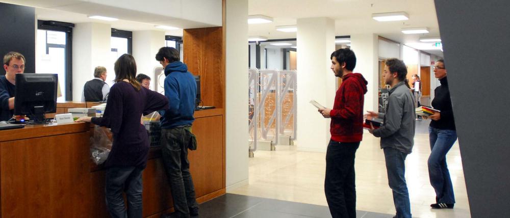 Studierende stehen in einer Bibliothek der Humboldt-Uni an der Buchausleihe.