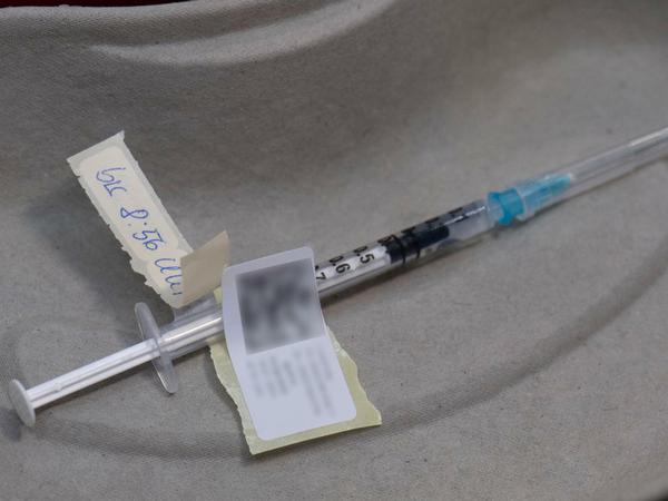 Eine Spritze mit dem Impfstoff von Biontech-Pfizer wird in eine Impfkabine gebracht.