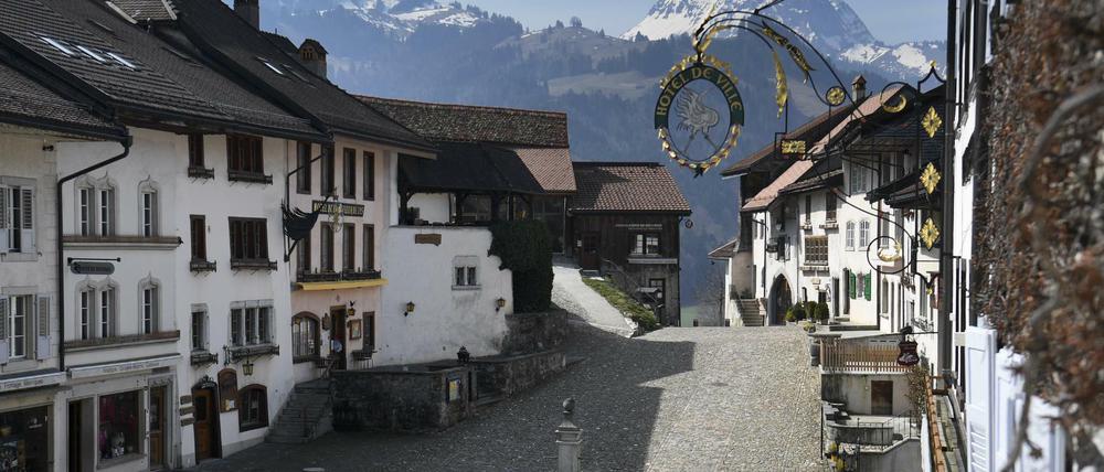 Häuser mit Restaurants, Läden und Herbergen stehen an der leeren Hauptstraße von Gruyeres, Schweiz, die sonst ein Touristenmagnet ist. 