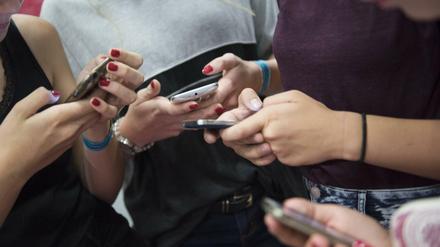 Ein Gruppe von Mädchen tippt auf ihren Smartphones herum.