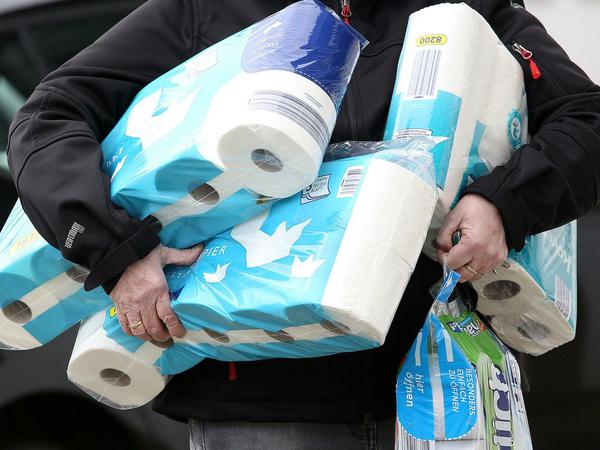 Ein Mann schleppt mehrere Großpackungen Toilettenpapier nach Hause.